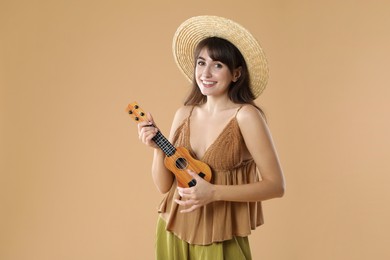 Photo of Happy woman playing ukulele on beige background