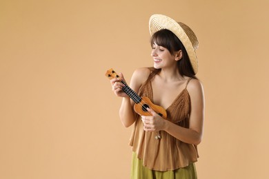 Happy woman playing ukulele on beige background, space for text