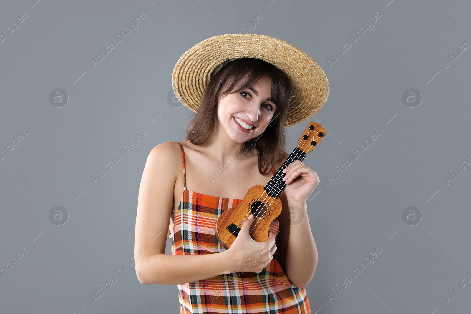 Photo of Happy woman playing ukulele on grey background, space for text