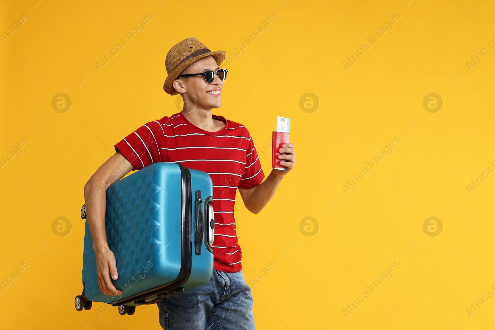 Photo of Happy traveller with suitcase, passport and ticket on yellow background