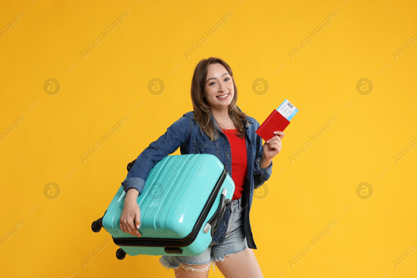 Photo of Happy traveller with suitcase, passport and ticket on yellow background