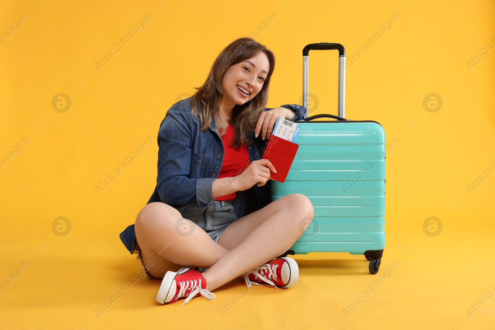 Photo of Happy traveller with suitcase, passport and ticket on yellow background