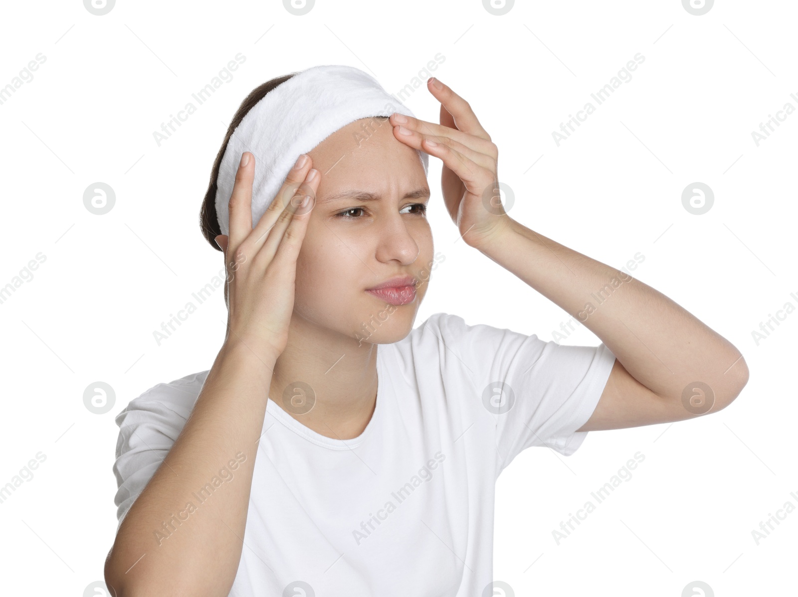 Photo of Upset teenage girl popping pimple on her face against white background. Acne problem