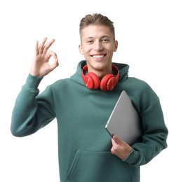 Photo of Happy young man with headphones and laptop showing OK gesture on white background