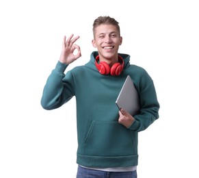 Photo of Happy young man with headphones and laptop showing OK gesture on white background