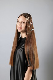 Photo of Teenage girl with stylish hair clips on light grey background