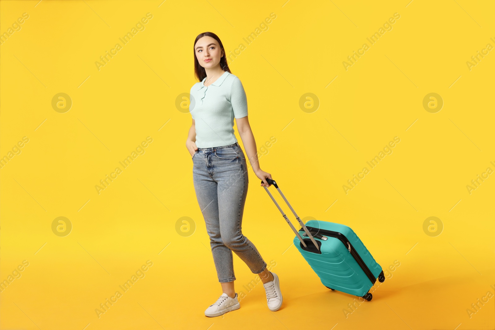 Photo of Young woman with suitcase on orange background