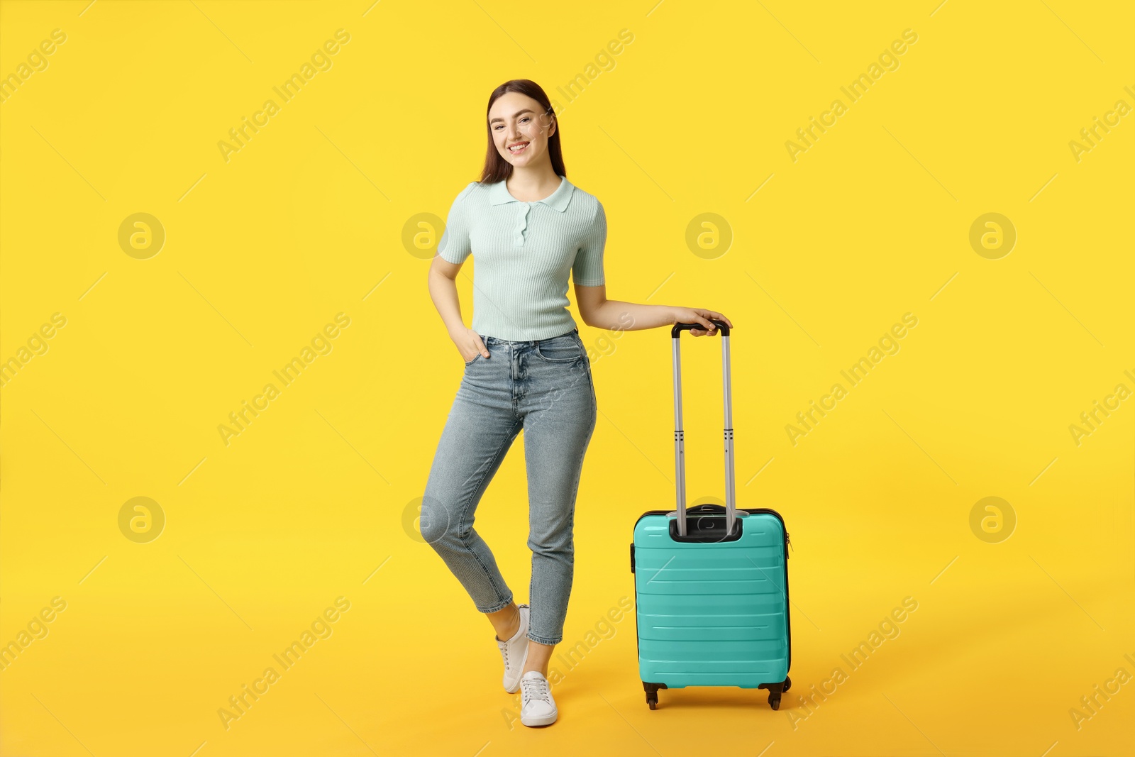 Photo of Young woman with suitcase on orange background