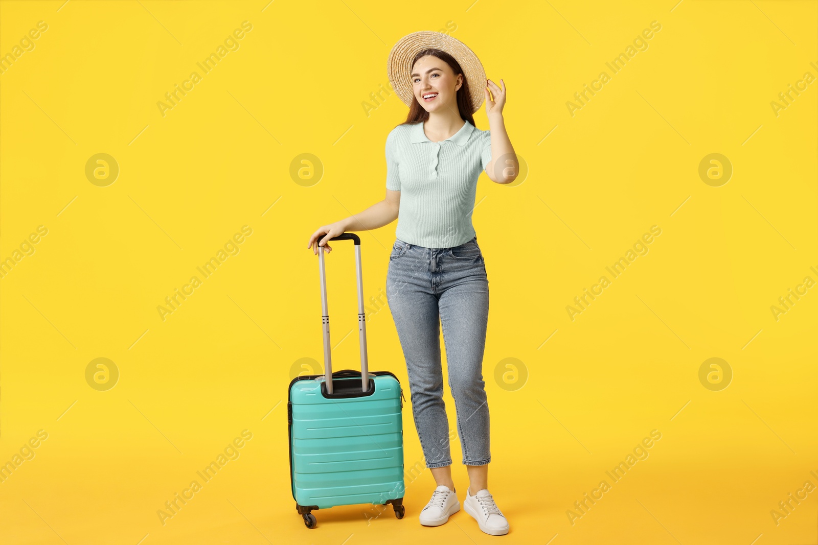 Photo of Woman in straw hat with suitcase on orange background