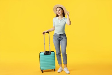 Photo of Woman in straw hat with suitcase on orange background