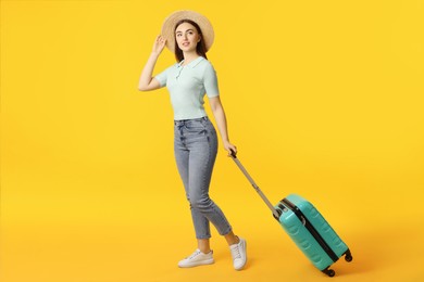 Photo of Woman in straw hat with suitcase on orange background