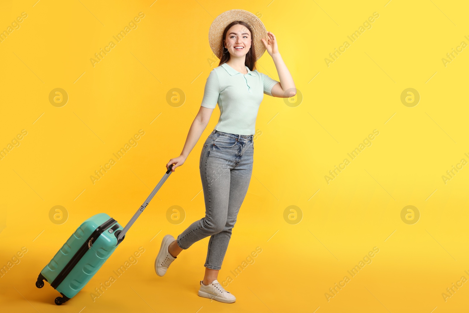 Photo of Woman in straw hat with suitcase on orange background