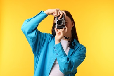 Photo of Woman taking picture with vintage camera on orange background