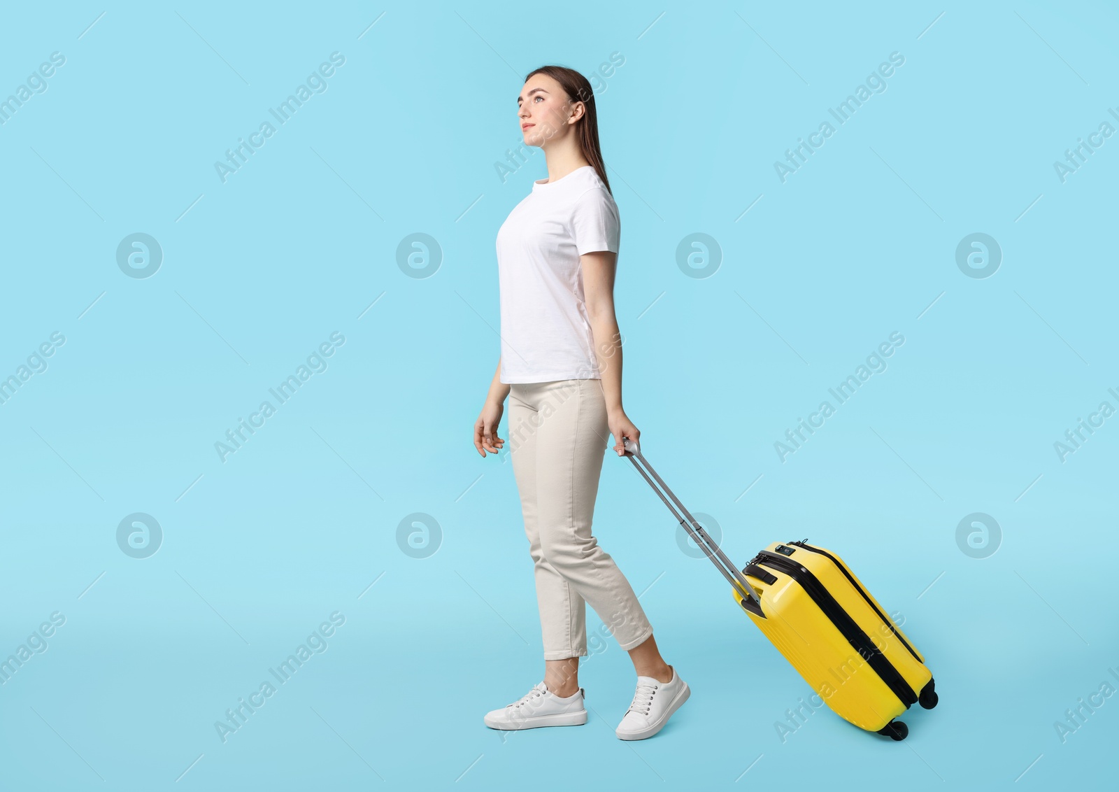 Photo of Woman with suitcase on light blue background