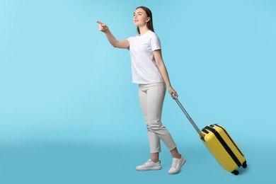 Woman with suitcase on light blue background