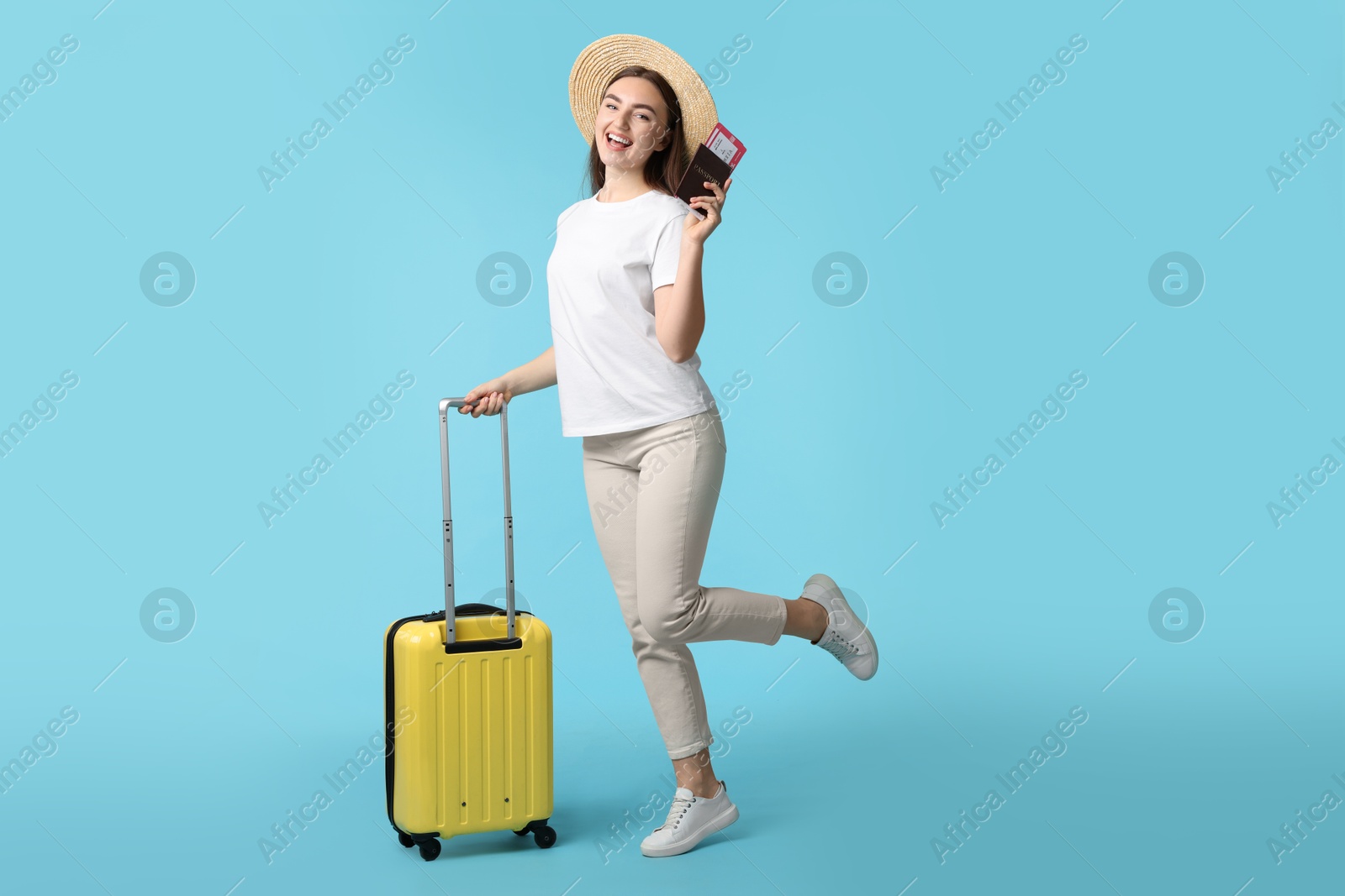 Photo of Woman with ticket, passport and suitcase on light blue background