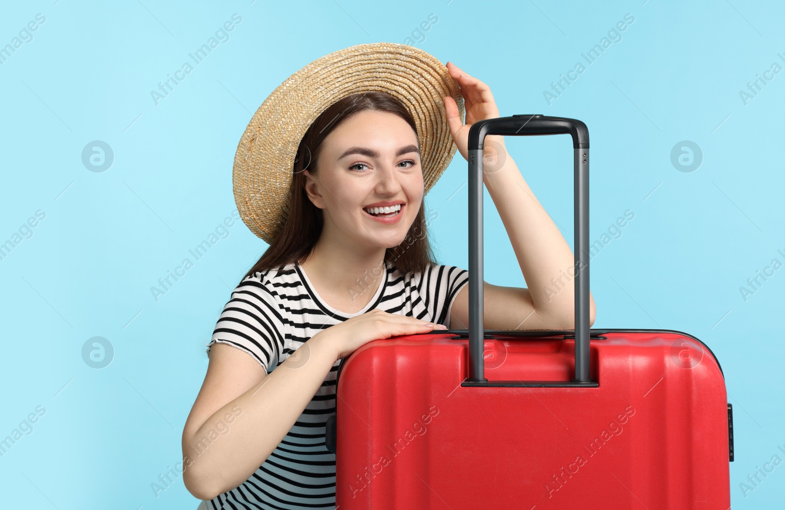 Photo of Woman in straw hat with suitcase on light blue background