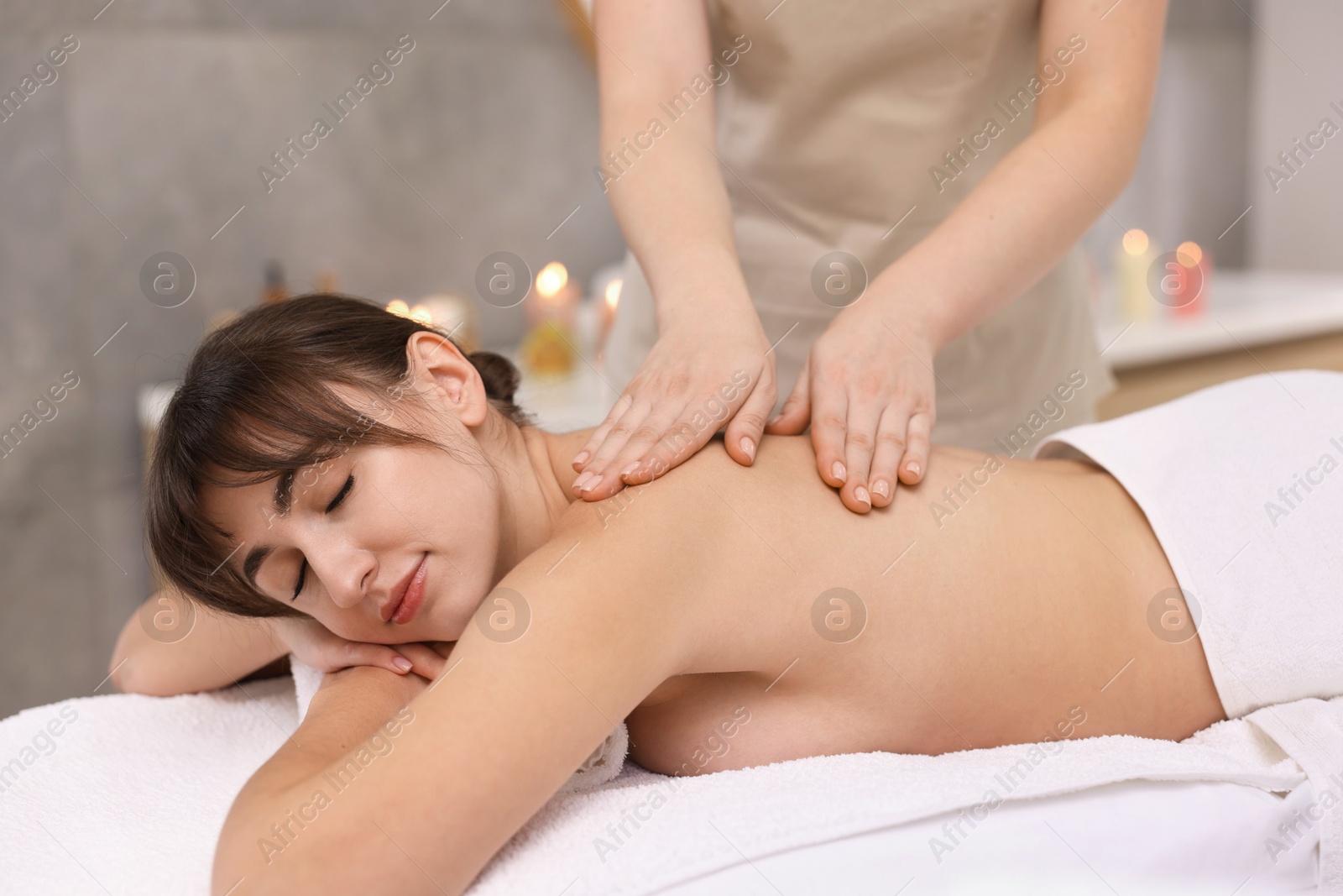 Photo of Young woman receiving back massage in spa salon