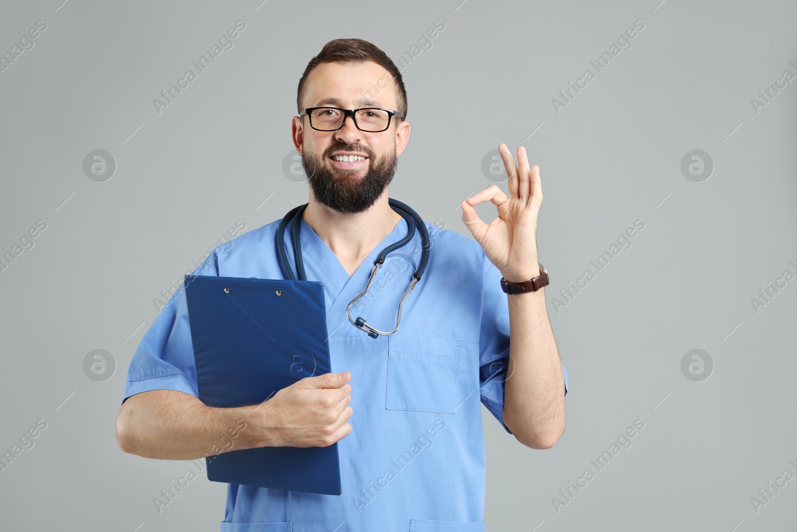 Photo of Doctor with clipboard showing okay gesture on grey background