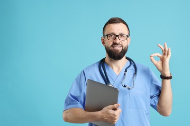 Doctor with laptop showing okay gesture on light blue background. Space for text