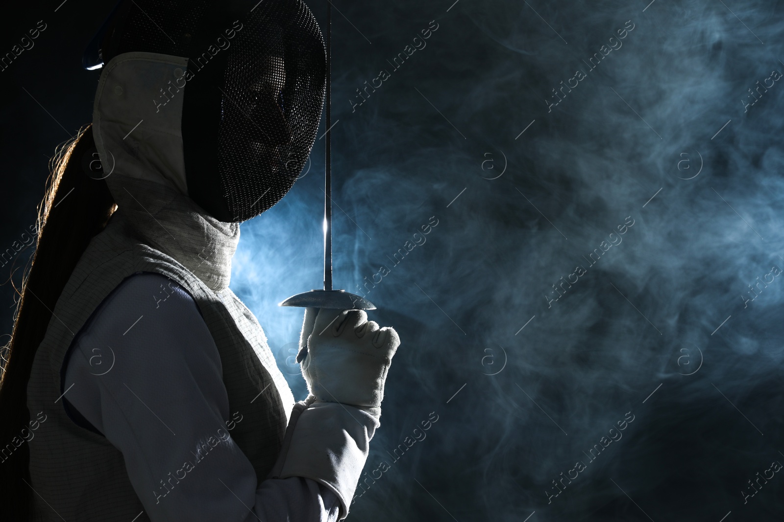 Photo of Fencer with epee in smoke on black background, space for text