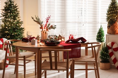 Photo of Christmas table setting with stylish dishware and festive decor indoors