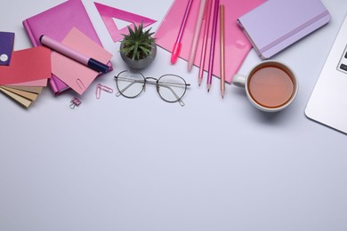 Photo of Designer's workplace with stationery, color palettes and cup of tea on grey table, flat lay. Space for text