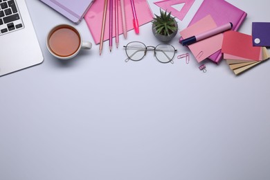 Photo of Designer's workplace with stationery, color palettes and cup of tea on grey table, flat lay. Space for text