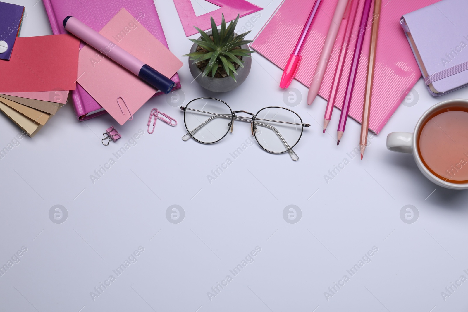 Photo of Designer's workplace with stationery, color palettes and cup of tea on grey table, flat lay. Space for text