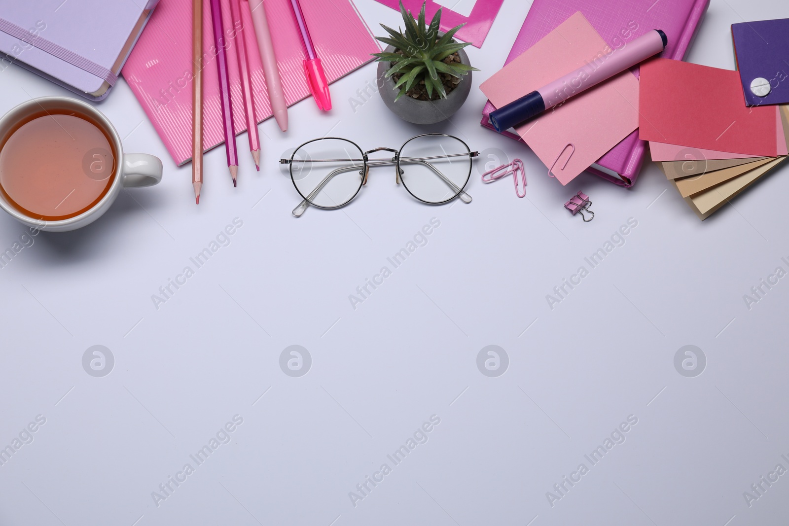 Photo of Designer's workplace with stationery, color palettes and cup of tea on grey table, flat lay. Space for text