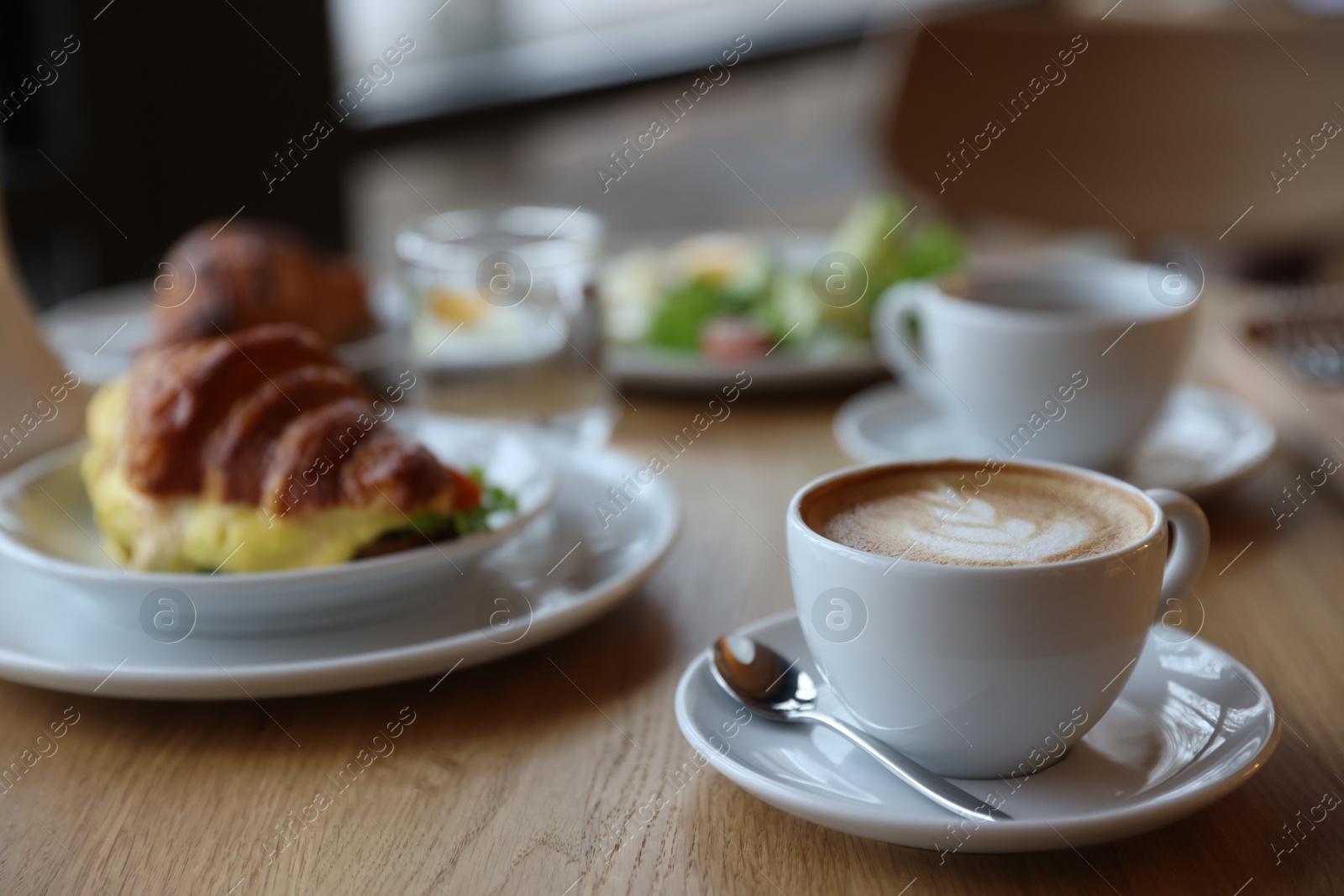 Photo of Delicious breakfast served on wooden table in cafe, closeup