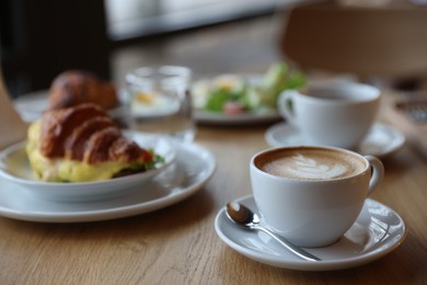 Photo of Delicious breakfast served on wooden table in cafe, closeup