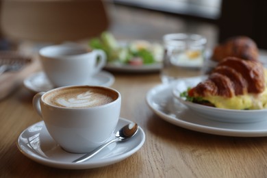 Photo of Delicious breakfast served on wooden table in cafe, closeup