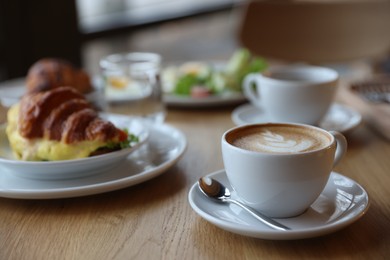 Photo of Delicious breakfast served on wooden table in cafe, closeup