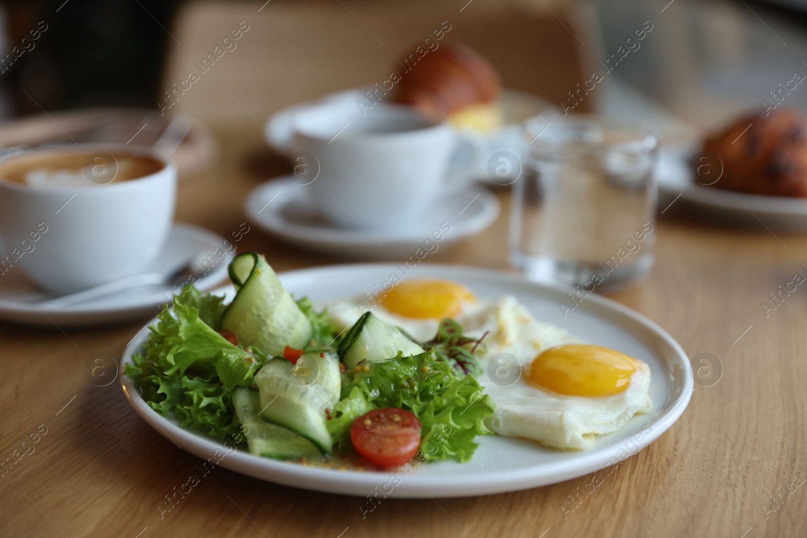 Photo of Delicious breakfast served on wooden table in cafe, closeup