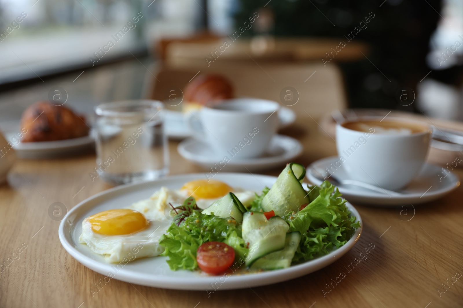 Photo of Delicious breakfast served on wooden table in cafe, closeup