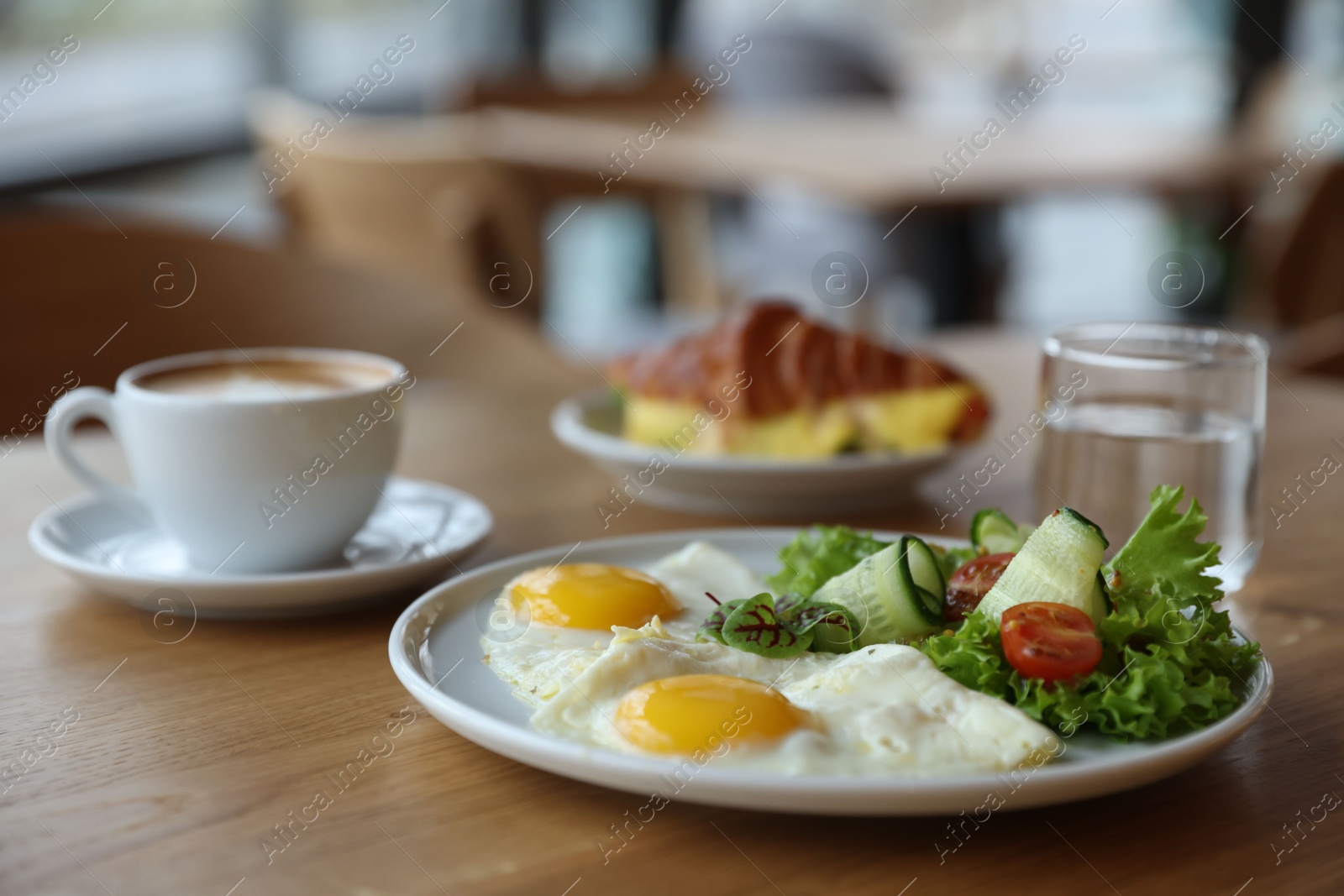 Photo of Delicious breakfast served on wooden table in cafe, closeup