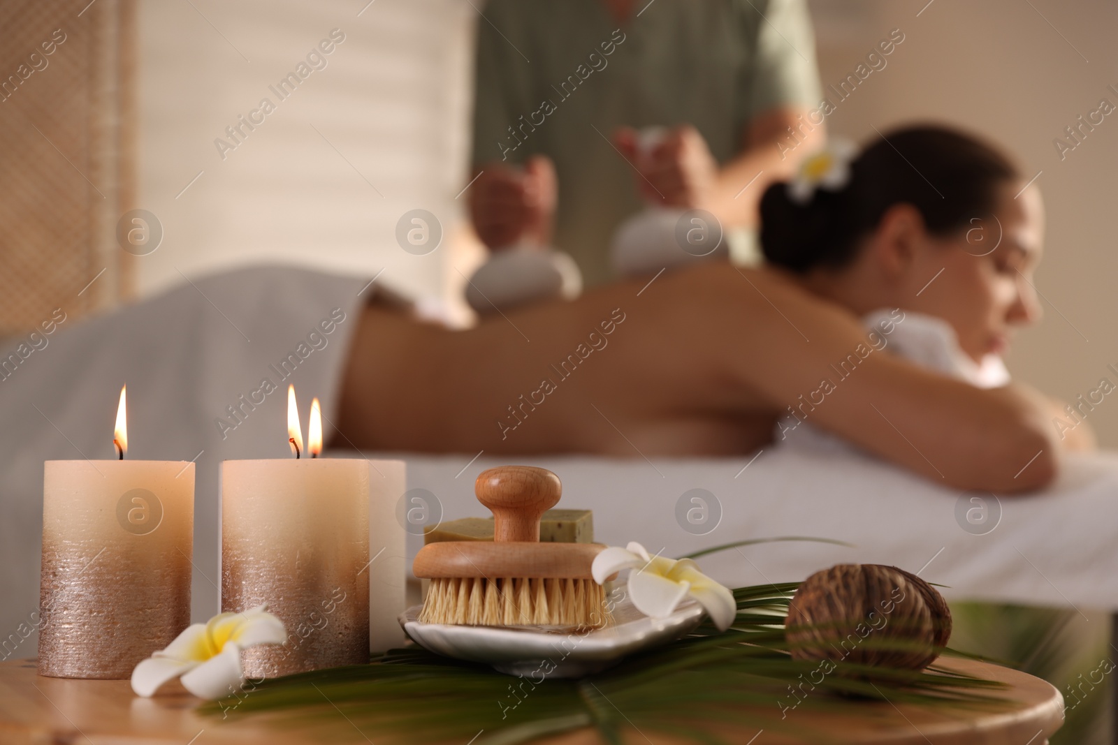 Photo of Woman receiving back massage with herbal bags in salon, focus on spa supplies