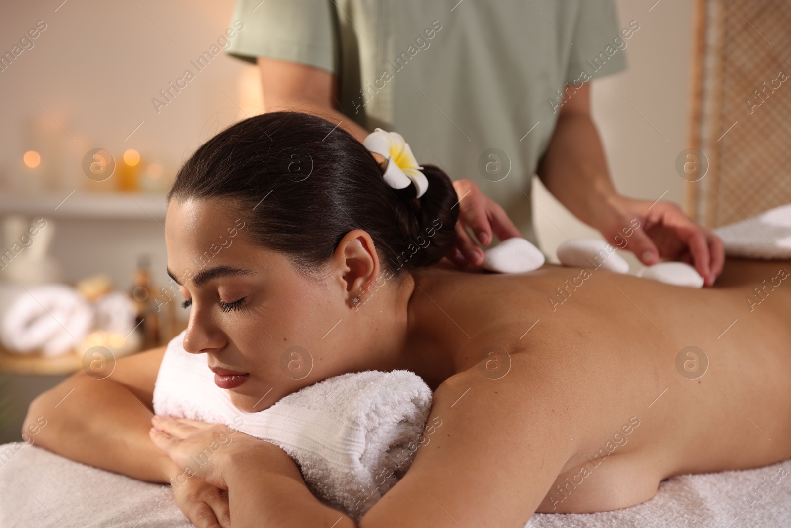 Photo of Woman receiving hot stone massage in spa salon