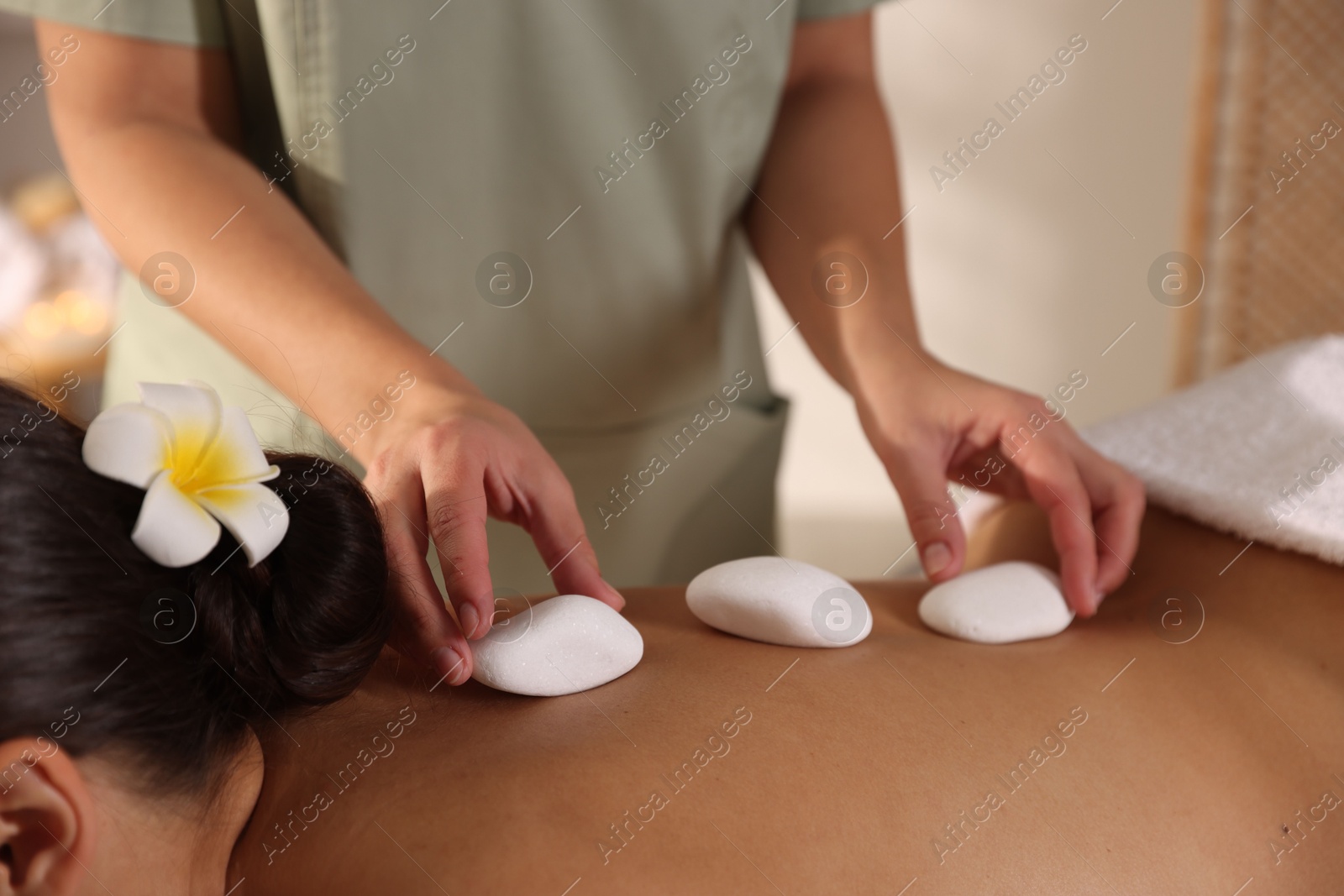 Photo of Woman receiving hot stone massage in spa salon, closeup