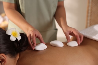 Photo of Woman receiving hot stone massage in spa salon, closeup