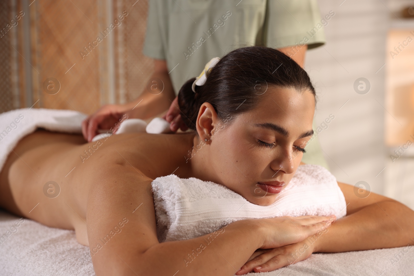 Photo of Woman receiving hot stone massage in spa salon