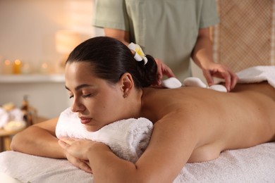 Photo of Woman receiving hot stone massage in spa salon