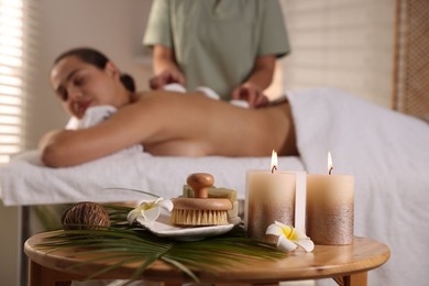 Woman receiving hot stone massage in salon, focus on spa supplies