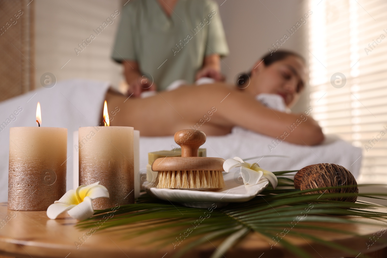 Photo of Woman receiving hot stone massage in salon, focus on spa supplies