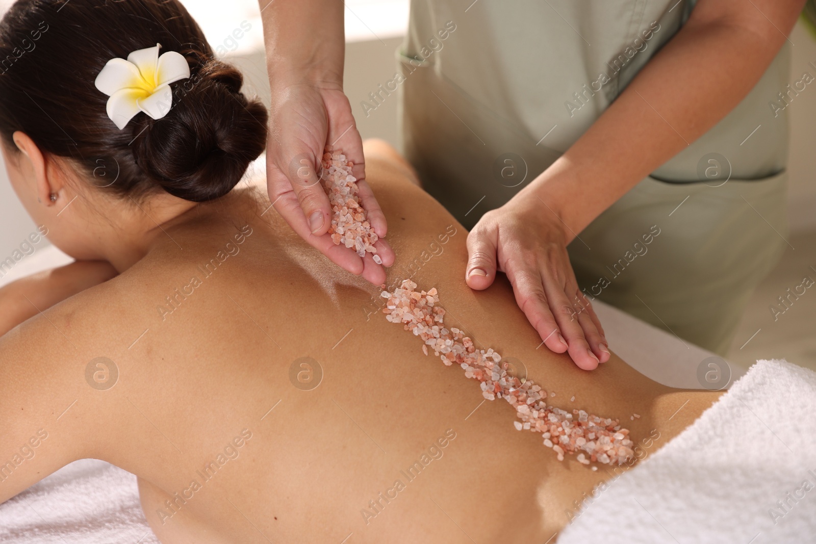 Photo of Woman receiving massage with sea salt in spa salon