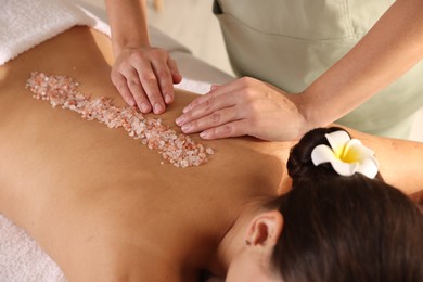 Photo of Woman receiving massage with sea salt in spa salon, closeup