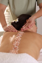 Photo of Woman receiving massage with sea salt in spa salon