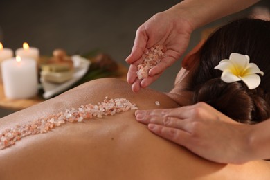 Photo of Woman receiving massage with sea salt in spa salon