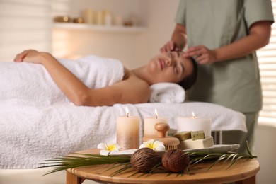 Photo of Woman receiving face massage in salon, focus on spa supplies